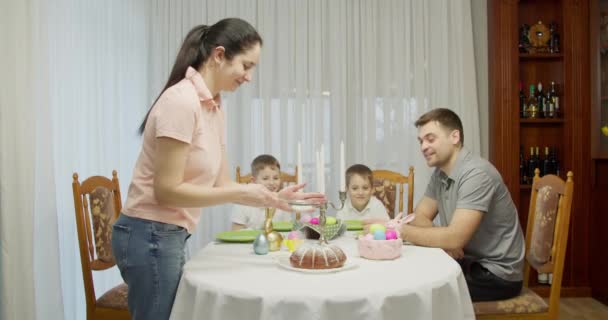 Glad kock mamma kvinna i rosa skjorta strö pulver på toppen av köksbordet hemma Begreppet matlagning matprocess. Pappa och två pojkar väntar på att få äta — Stockvideo