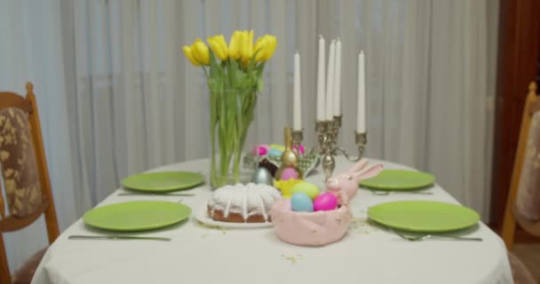 Paastabel. op de tafel liggen beschilderde eieren, gele tulpen, cake — Stockvideo