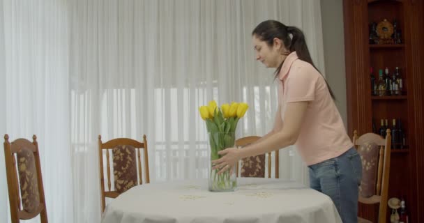 Brunette vrouw zet gele tulp aan tafel. Bestel de gele tulpen mooi. het ruikt naar frisheid — Stockvideo