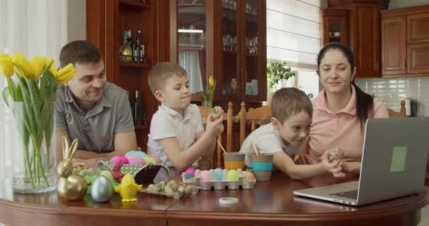 Hermosa familia hablando de videollamadas usando computadora. los niños muestran huevos de Pascua pintados por ellos — Vídeos de Stock