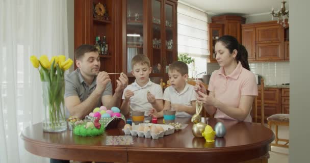 Lukisan Paskah Keluarga dengan dua anak laki-laki mewarnai telur Paskah — Stok Video