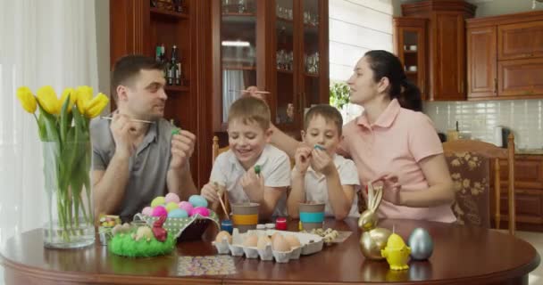 Ambiente pascal. mãe e filho querem pintar o pai sujo com tinta — Vídeo de Stock