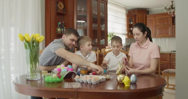 Lukisan Paskah Keluarga dengan dua anak laki-laki mewarnai telur Paskah — Stok Video