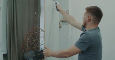 Bir adam silindirle duvar boyuyor. Odada tamirat yapan bir adam. Modern iç mekan. Bir adam onarımlar yapar. İnşaat ve onarım. Onarım işi
