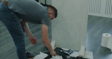 Modern iç mekan. Bir adam silindirle duvar boyuyor. Bir adam onarımlar yapar. Odada tamirat yapan bir adam. İnşaat ve onarım. Onarım işi