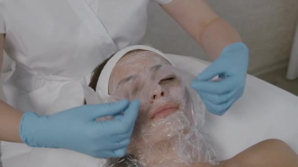 Een medisch schoonheidsspecialiste brengt een masker aan op een jong meisje. — Stockvideo