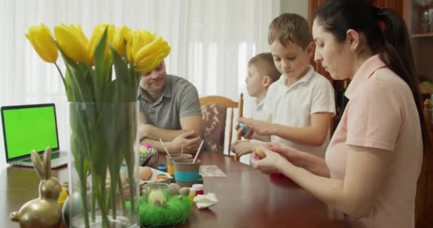 Onnellinen perhe maalaus pääsiäismunia keittiössä — kuvapankkivideo