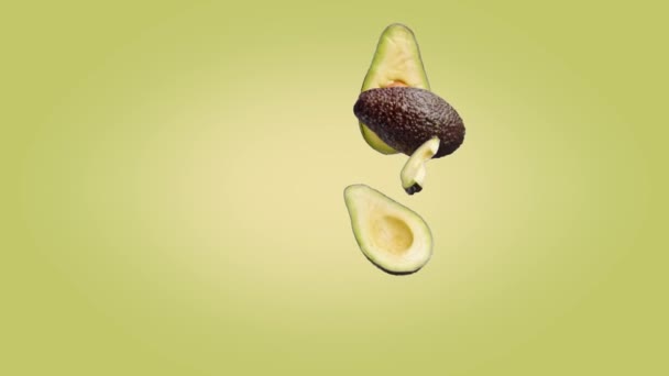 Avocado половинки і шматки, які падають на жовтий зелений фон. — стокове відео