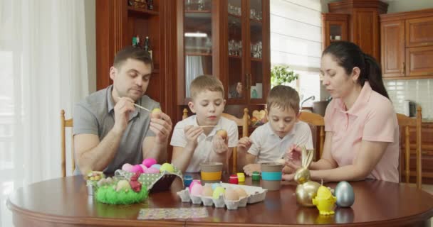 Ευτυχισμένη οικογένεια ζωγραφίζει πασχαλινά αυγά στην κουζίνα — Αρχείο Βίντεο