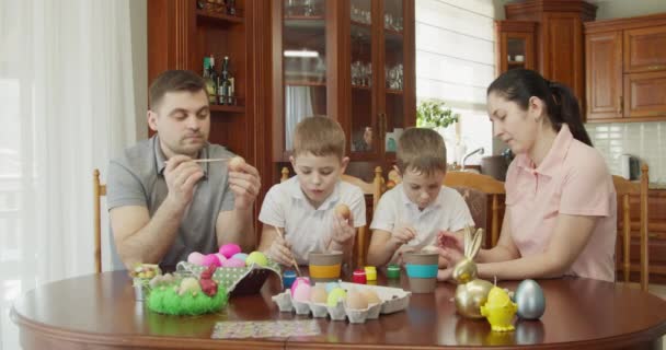 Glückliche Familie bemalt Ostereier in Küche — Stockvideo