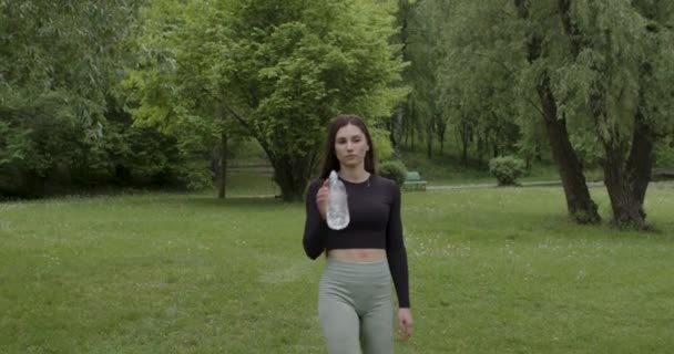 做完瑜伽训练的女运动员在公园里散步喝水 — 图库视频影像
