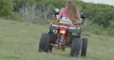 Özgür bir kadın yeşil çimlerin üzerinde ormanın yakınında bir avluya biner. ATV off-road macerası. Kız Dörtlü bisiklet, macera, seyahat, turizm kullanıyor. Yazın açık hava aktiviteleri, açık hava seyahatleri
