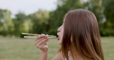 Beyaz bir kutudan servis edilen bambu çubuğu makizushi suşi yiyen aç ve tatmin olmuş 20 yaşındaki esmerin yakın plan görüntüsü..