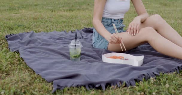Lese Sedí Trávě Dívka Bílém Tričku Modrých Zástěrách Sushi Rolku — Stock video