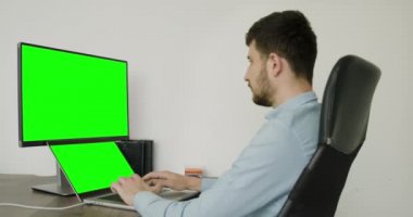 boy in blue shirt in a modern office typing on computer. green screen concept