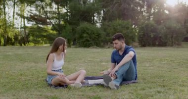 a man and a woman sitting on a blanket in the park discussing business and marketing ideas and eating sushi