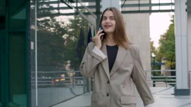 portrait of a business woman talking on the phone. brunette woman walks outside near the business center where she works. the concept of a business woman satisfied with her job