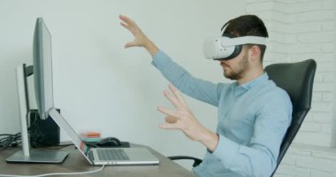 elegantly dressed young man wearing 3d glasses analyzing several virtual images marvels at what he sees. Virtual technologies and job with many possibilities