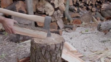 man working to split wood with an axe, then with his hands. man prepares wood for winter