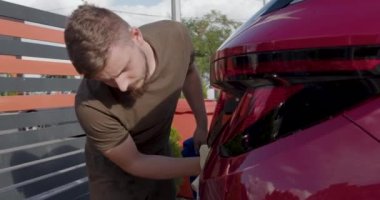 worker wiping the car with a multifibre cloth after a professional wash. Outdoor image.