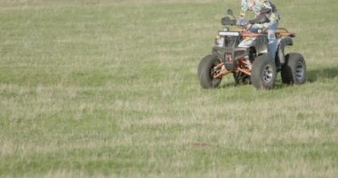 ATV 'de hız yapan genç bir adamın yan görüntüsü. Bir ATV 'nin tekerleklerine yakın çekim. Aşırı tatil konsepti