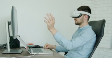 İş adamı, klasik giyinmiş, bir finans şirketini 3 boyutlu gözlüklerle analiz ediyor. Modern ofis ve modern teknolojiler. Ciddi bir adam iş başında.