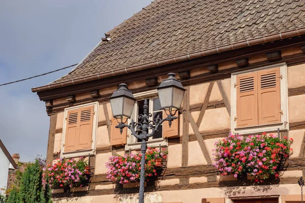 Equisheim, France. Old homes with beautiful architecture in Alsace. Flowers hang from windows.