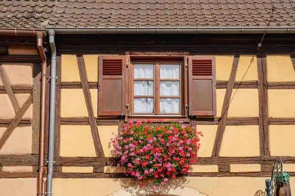 Equisheim, France. Old homes with beautiful architecture in Alsace. Flowers hang from windows.