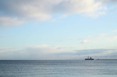 Açık deniz. Denizin ortasında bir gemi gemisi. Bulutlu bulutlu hava. Su dalgaları. Denizde güneş.