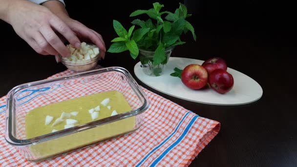 Äpple strudel recept. degen hälls i en bakform på svart bakgrund. på bordet bredvid ett glas mynta och 3mogna äpplen — Stockvideo