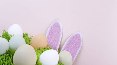 Tavşan kulakları ve doğal renkte yumurtalar mavi arka planda yeşil gerçek çimenler üzerinde.