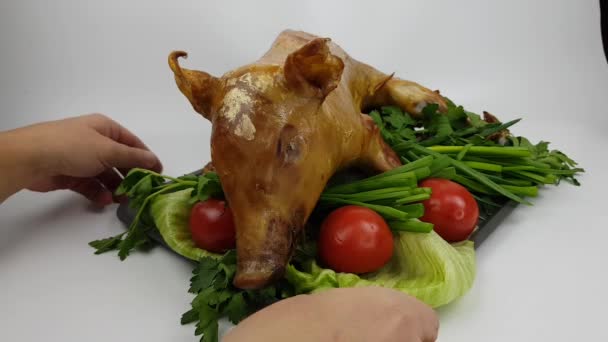 Un cochinillo o cerdo asado en una saliva o en el horno se encuentra en una bandeja. plato de cerdo festivo decorado con verduras sobre un fondo gris — Vídeos de Stock
