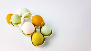 Doğal gölgeli çok renkli yumurtalar dekore edilir ve açık arkaplanda yumurta hücrelerinde yatar. Kutsal Paskalya Günü için süslemeler.