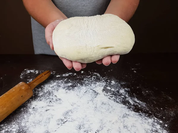 Kok Houdt Gistdeeg Zijn Handen Een Donkere Achtergrond Ligt Een — Stockfoto