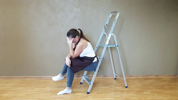 Eine Frau Sitzt Auf Einer Bauleiter Und Hält Ihren Kopf — Stockfoto