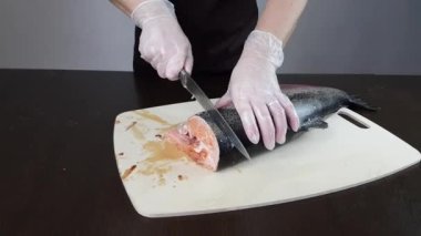 Aşçı taze çiğ alabalık balığı keser. Bir balık yemeği hazırla.