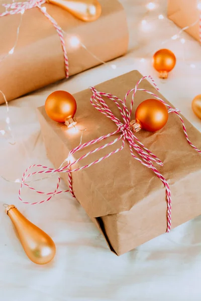 Üstünde altın ışıklar olan Noel hediyeleri. Altın Noel ağacı oyuncaklarıyla parlak çelenkler, parlak bir arka planda Noel hediyeleri. Parlak ışıklar, hediye kutuları üzerinde hafif bir çelenk.