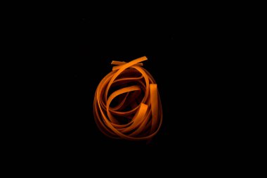 Koyu bir arka planda kuru macun. Doğal tagliatelle peynirinden yapılmış makarna. Taze çiğ yumurtadan yapılmış İtalyan makarnası. Makarna yuvası. Çiğ pappardelle, spagetti ve yumurtalı makarna, yakın plan..