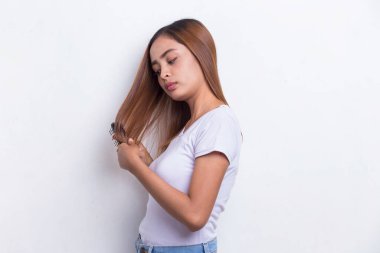 Genç, güzel Asyalı bir kadın uzun saçlarını tarıyor beyaz arka planda izole edilmiş bir tarakla.