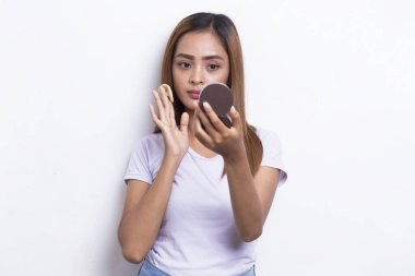 Güzel Asyalı kadın beyaz arka planda kozmetik makyaj tozu uyguluyor.