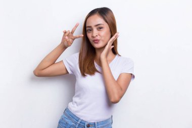 Güzel genç Asyalı kız beyaz arka planda barış ya da zafer işareti gösteriyor.
