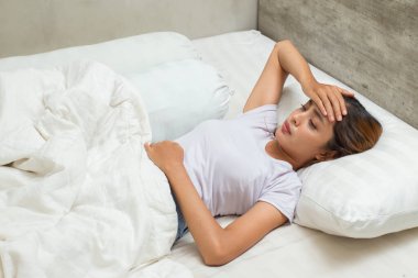 Asyalı kadın hasta, ateşi var ve öksürükle evde uyuyor.