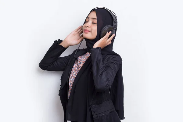 白い背景に隔離されたヘッドフォンで音楽を聴くヒジャーブを持つアジアのイスラム教徒の女性 — ストック写真