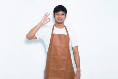 Asyalı önlüklü adam mutlu bir şekilde gülümsüyor.