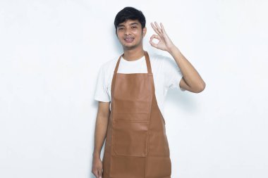 Asyalı önlüklü adam mutlu bir şekilde gülümsüyor.