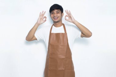 Asyalı önlüklü adam mutlu bir şekilde gülümsüyor.