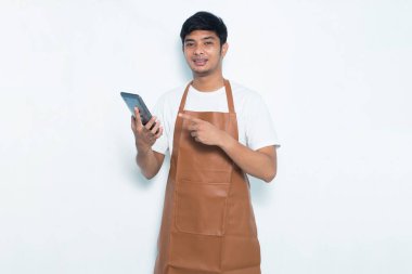 Mutlu Asyalı genç barmen ya da garson kız beyaz arka planda izole edilmiş cep telefonu kullanıyor.