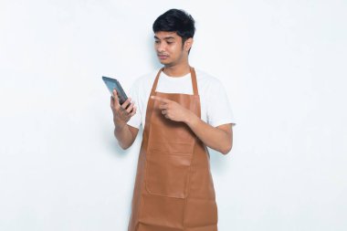 Mutlu Asyalı genç barmen ya da garson kız beyaz arka planda izole edilmiş cep telefonu kullanıyor.