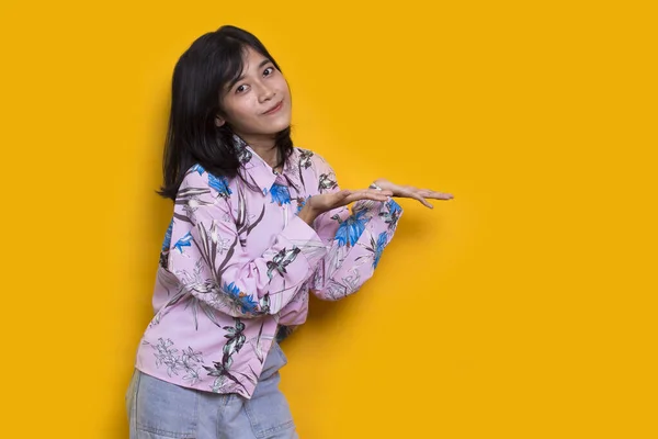 Sarı Arka Planda Farklı Yönleri Gösteren Asyalı Genç Bir Kadın — Stok fotoğraf