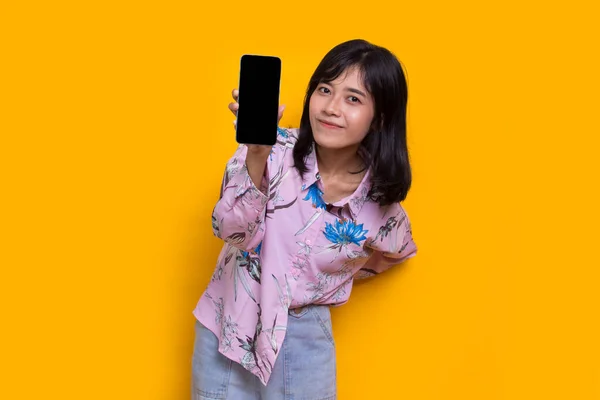 Young Beautiful Asian Woman Demonstrating Mobile Cell Phone Isolated Yellow — Stockfoto